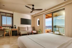 a bedroom with a bed and a couch and a tv at Enorme Infinity Elounda - Adults Only in Elounda