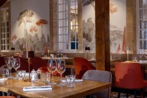 a restaurant with a wooden table with wine glasses on it at Château Saint Gilles - Bayeux in Guéron