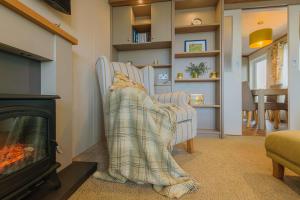a living room with a fireplace and a blanket at Hot Tub Lodge 31 Cameron, St Andrews in St. Andrews