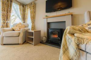 a living room with a fireplace with a television above it at Hot Tub Lodge 31 Cameron, St Andrews in St. Andrews