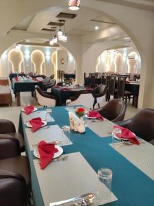 ein Esszimmer mit Tischen und Stühlen mit roten Servietten in der Unterkunft Hotel H Plus in Kurukshetra