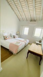 a white bedroom with two beds and a table at Pego Beach House in Grândola +18 photos