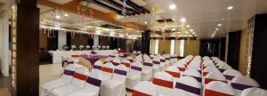 a banquet hall with white chairs and tables in a room at Hotel Cosmos in Lucknow