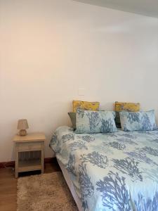 a bedroom with a bed with blue and white sheets and a table at Le Grec Wine Tram Apartment #2 in Franschhoek
