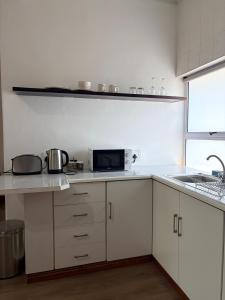 a kitchen with white cabinets and a counter top at Le Grec Wine Tram Apartment #2 in Franschhoek