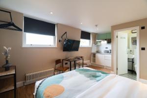 a bedroom with a large bed and a kitchen at Lamington Apartments - London Hammersmith in London