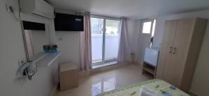 a small bedroom with a bed and a window at Yard Paradise Rooms in Dhërmi