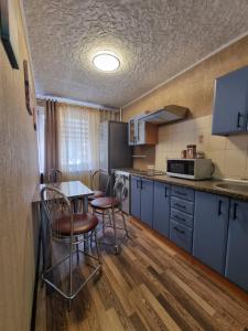 a kitchen with blue cabinets and a table and chairs at Airida Forest Apartment in Druskininkai