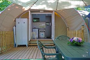 a tent with a green table and chairs and a table with flowers at Villaggio Camping delle Rose - Gatteo a Mare in Gatteo a Mare