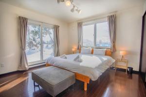 a bedroom with a large bed and large windows at North Furano House in Kami-furano