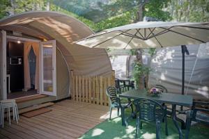 a tent with a table and chairs and an umbrella at Villaggio Camping delle Rose - Gatteo a Mare in Gatteo a Mare