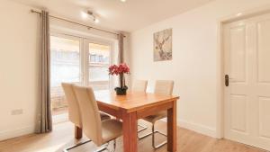 a dining room table with chairs and a vase of flowers at Colindale 4 bedroom house with garden and 2 parking spaces in Colindale