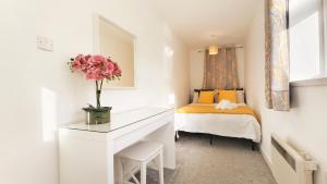 a bedroom with a bed and a desk with a vase of flowers at Colindale 4 bedroom house with garden and 2 parking spaces in Colindale