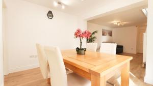 a dining room with a wooden table and white chairs at Colindale 4 bedroom house with garden and 2 parking spaces in Colindale +34 photos