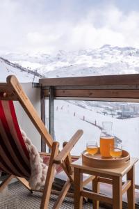 a chair and a table with two glasses of orange juice at Résidence Pierre & Vacances Les Combes in Les Menuires