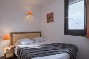 a bed with two pillows and a window in a room at Résidence Pierre & Vacances Les Combes in Les Menuires +30 photos