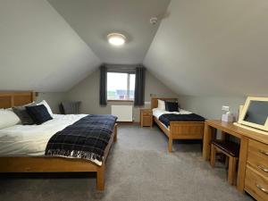a bedroom with two beds and a desk and a television at Karrawa Guest House in Kirkwall