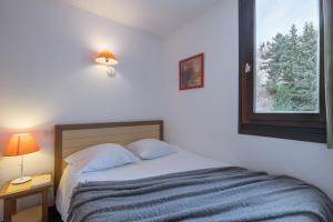 a bedroom with a bed with two pillows and a window at Résidence Pierre & Vacances Les Combes in Les Menuires