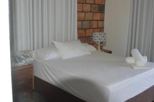 a bed with white sheets and pillows in a bedroom at lodge3a in Ponta do Ouro +56 photos