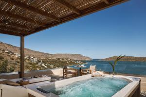 a hot tub on a patio with a view of the ocean at Enorme Infinity Elounda - Adults Only in Elounda