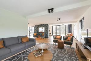 a living room with a couch and a table at Villa Vechtrijk | 12 persons in Gramsbergen