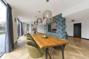 a dining room with a long wooden table and chairs at Villa Vechtrijk | 12 persons in Gramsbergen