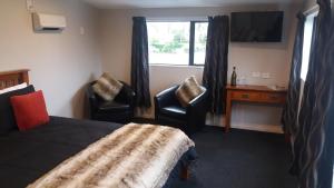 a bedroom with a bed and two chairs and a desk at Stream View in Christchurch
