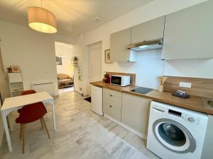 a kitchen with a washing machine and a table at L'Atrium - Cour intérieure & box vélo, rdc in Castelnaudary