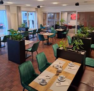 a restaurant with wooden tables and green chairs at Hotel & Apart4you in Dorfen