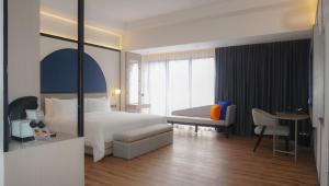 a hotel room with a bed and a desk and a chair at Nusatu by ARTOTEL - Semarang in Semarang