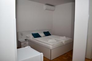 a small white bedroom with a bed with blue pillows at Villa Rosa Rooms in Punat +85 photos