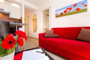 a red couch in a living room with red flowers at Meeresblick Fewo Strandnest - in Baabe