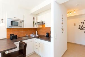 a kitchen with white cabinets and a table and a microwave at Meeresblick Fewo Strandnest - in Baabe