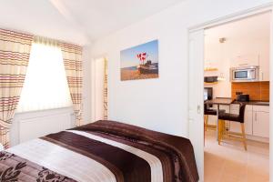 a white bedroom with a bed and a kitchen at Meeresblick Fewo Strandnest - in Baabe +2 photos
