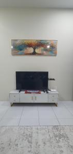 a white room with a television and a painting on the wall at REZEKI MUEZZA 3BR2B Cozy Homestay in Teluk Intan