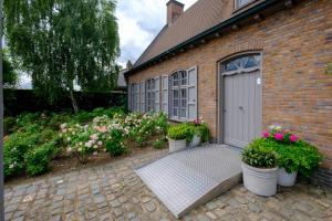a brick house with a garage with pots of flowers at Rozerie BV in Waregem