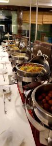 a row of pans of food on a table at Hotel Cosmos in Lucknow
