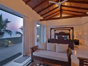 a bedroom with a bed and a couch and a window at Florain Otium Talpe in Unawatuna