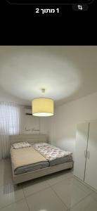 a bedroom with a bed with a light above it at Luba in H̱olon