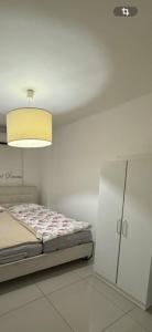 a white bedroom with a bed and a light at Luba in H̱olon