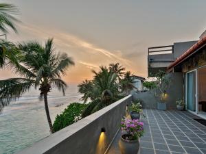 a house with a balcony with palm trees and the ocean at Florain Otium Talpe in Unawatuna