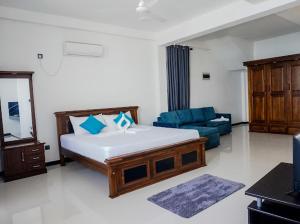a bedroom with a large bed and a blue couch at Ocean River View in Ambalangoda