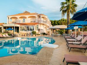 a pool with chairs and umbrellas next to a building at Hotel Panorama in Koukounaries
