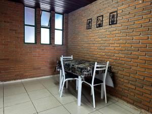 a table and chairs in a room with a brick wall at Quarto confortável no Centro in Botucatu