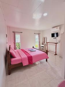 a bedroom with a pink bed and a table at Queue&Bright Resort in Ban Pa Tung (7)