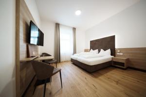 a bedroom with a bed and a desk and a television at Kolpinghaus Bolzano in Bolzano +28 photos