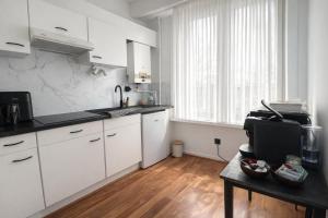 a kitchen with white cabinets and a wooden floor at 2 Bedroom Apartment for Families and Business, Tram and Bus in Front in Antwerp