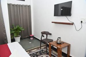a room with a chair and a tv on a wall at pitambara studio apartment with kitchen in Karadoho