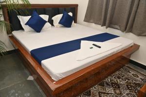 a bed with blue and white pillows and a laptop on it at pitambara studio apartment with kitchen in Karadoho