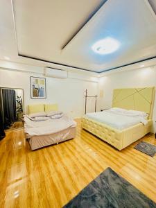 two beds in a large room with wooden floors at The Penthouse With Outdoor Jacuzzi Private Rooftop Solar Powered Energy in Puerto Princesa City